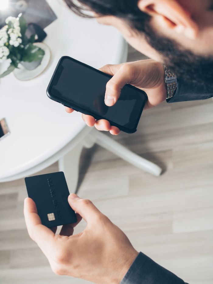 A man using a smartphone and credit card to make an online payment, illustrating digital finance concepts.